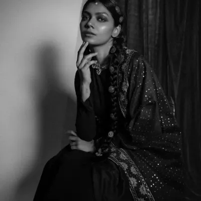A moody, black and white portrait from the 'Amodini' series. This look features a dark Anarkali with an embellished dupatta and traditional hair jewelry, creating a vintage, cinematic feel.