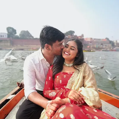A candid moment of affection on a boat in Varanasi, with seagulls flying past. These are the unscripted, joyful moments that make a pre-wedding shoot special.