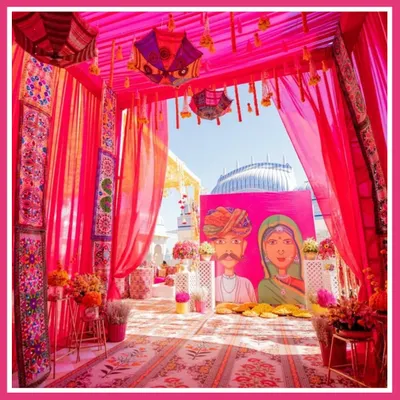 For a Rajasthani Mela theme, I created this vibrant entrance with bright pink drapes, traditional painted umbrellas, and custom artwork, instantly transporting guests to Rajasthan.