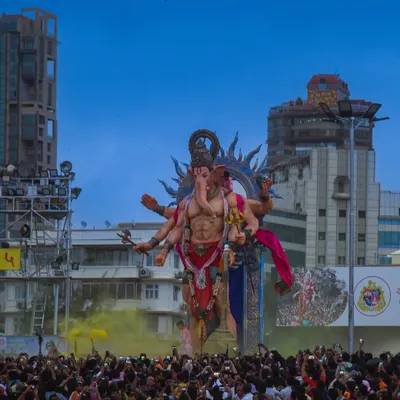 A colossal Ganesha idol towers over a massive crowd during the Ganpati Visarjan festival in Mumbai. The scale of the celebration is immense.