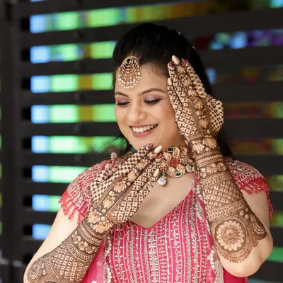 A happy bride admiring her beautiful, detailed mehndi.