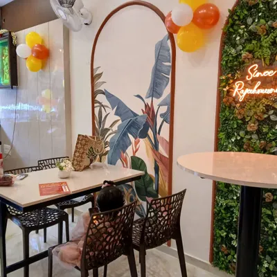 A closer look at the seating area in the cafe project. The custom arched mural with tropical leaf patterns creates a beautiful backdrop. We paired it with durable tables and comfortable, modern chairs to complete the look.