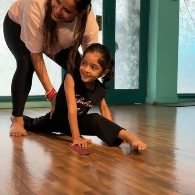 A smiling student works on her splits with my guidance. I ensure every stretch is done correctly to build flexibility safely and celebrate each small achievement.