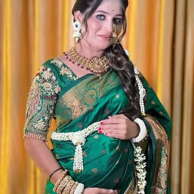 A beautiful mom-to-be wearing a classic all-white floral set for her baby shower. The design includes a traditional kamarbandh (waist belt) and hand kalire made from fresh Tagar buds.
