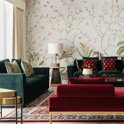 A full view of a living room featuring my floral garden mural. The design serves as a soft, artistic backdrop that unifies the space and complements the rich jewel tones of the furniture.