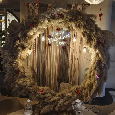 A rustic and romantic Valentine's Day backdrop. I used a large circular frame covered in fluffy pampas grass, with a "Happy Valentines Day" neon sign and hanging lights for a warm, bohemian feel.