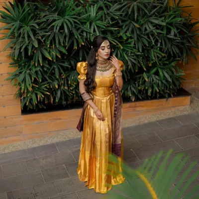 A full-length shot of a client in a beautiful golden gown, perfect for a reception or engagement. The makeup is kept elegant and classic, with soft waves in her hair.