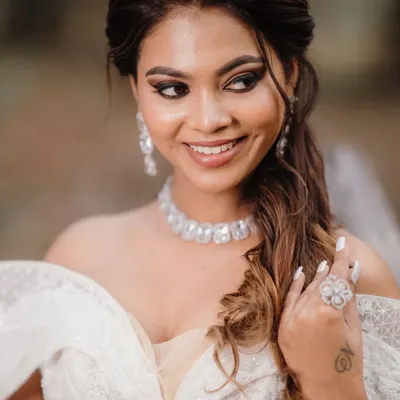 A happy, smiling bride in her beautiful white gown. The makeup is soft and radiant, with a focus on a flawless complexion and a pretty pink lip.