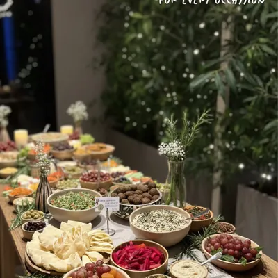 A full view of one of my custom grazing tables set up for a house party. I style each table with an assortment of dips, crackers, breads, olives, fruits, and fresh herbs to create a stunning and delicious spread for your guests.