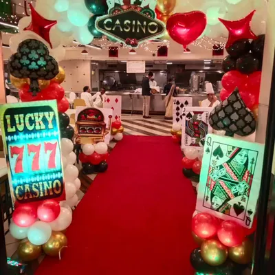 The entrance to our casino themed event, featuring a red carpet walkway flanked by illuminated signs and playing card cutouts. This setup immediately transports guests into the theme.
