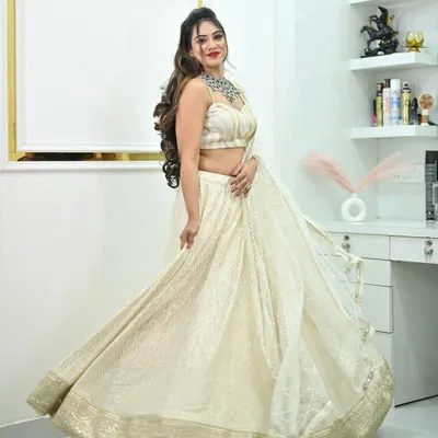 A beautiful ivory lehenga with delicate chikankari work and a gold border. The model's twirl shows off the graceful movement and full flare of the skirt.