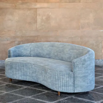 The Ivy Sofa, with its fluid, curved form and pleated upholstery, is designed to be a statement of quiet presence. It offers a gentle embrace, making it a perfect centerpiece for a living room that values both style and deep comfort.
