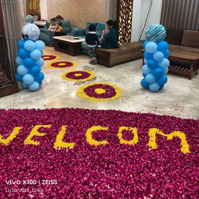 A heartwarming 'Welcome Baby' decoration for a baby boy's arrival. The floor is decorated with a large message made from flower petals and flanked by blue balloon pillars.