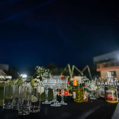 An elegant bar setup at night, with carefully arranged glassware, premium spirits, and fresh floral decorations. We believe the bar should be as beautiful as the rest of your event decor.