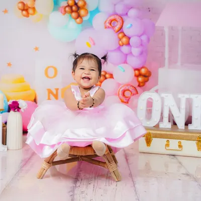 A perfect first birthday portrait with a sweet candy-themed setup. Her joyful laugh is the highlight of this entire session.