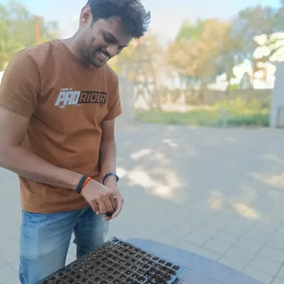 It all begins here. My engineer Sumanth is helping sow seeds for the next cycle. This careful, hands-on work ensures we start with strong, viable plants for your farm.