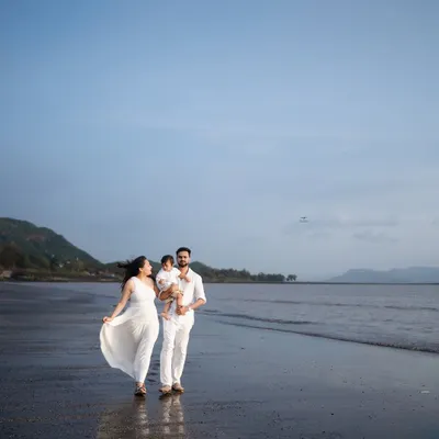 A beautiful family walk along the shoreline. The expecting mother's white dress flows in the breeze, creating a sense of freedom and joy in this outdoor maternity photo.