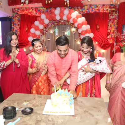 The cake-cutting ceremony at a newborn's welcome party, with the whole family gathered around, clapping and celebrating the new arrival. A classic, happy moment.