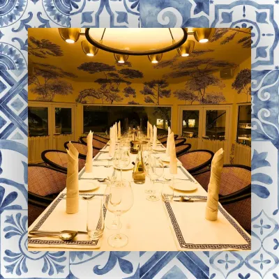 A long table set for a large group in our indoor dining room. The elegant wallpaper and lighting create a sophisticated atmosphere for any formal event.