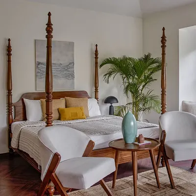 A magnificent colonial-style four-poster bed made from solid teak, featured in a luxury Alibag hotel. Paired with modern armchairs and a side table, it creates a perfect blend of classic and contemporary design.