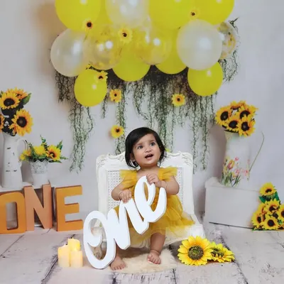 A wide shot of the complete sunflower-themed setup, showing how all the elements like props, balloons, and lighting come together for a first birthday portrait.