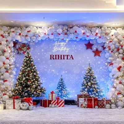 An elegant "Winter ONE-derland" theme for Rihita's first birthday. The stunning balloon arch is filled with white, silver, and red ornaments, framing a backdrop of sparkling snow and decorated Christmas trees.
