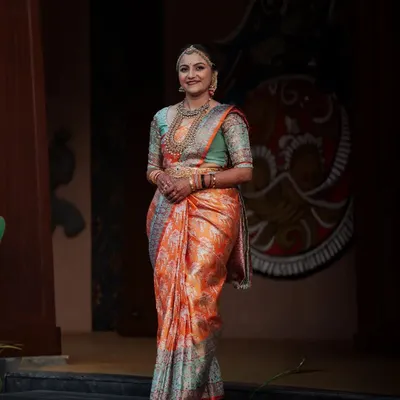 A stunning full-length portrait of a South Indian bride in her gorgeous orange and teal Kanjeevaram saree. We take the time to capture these elegant shots that showcase the entire bridal look.