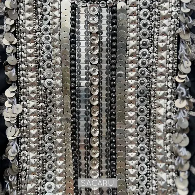 A detailed view of the meticulous hand embroidery on a brocade halter neck piece, showcasing rows of silver metal sequins and beads.