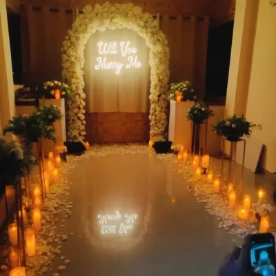 The perfect surprise proposal. I created this romantic scene with a pathway of candles, a beautiful white floral arch, and a glowing "Will You Marry Me" sign.