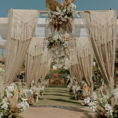 A Tulum-inspired welcome lunch. The couple wanted a neutral-toned, chic, and soulful vibe, so we used macrame curtains, pampas grass, and earthy textures to create this serene and stylish entrance.