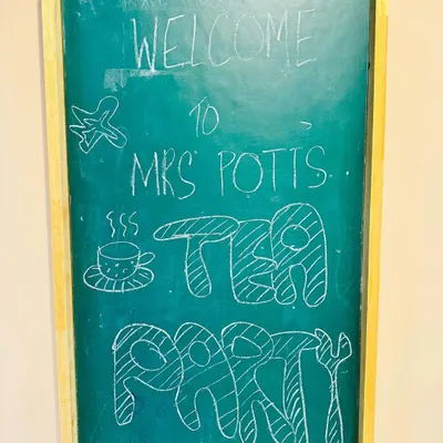 A charming welcome to our special event. A hand-drawn chalkboard sign announces "Welcome to Mrs. Potts' Tea Party," setting a playful and inviting tone right from the start.