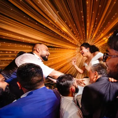 The bride and groom are lifted up by friends and family on the dance floor. The radial lights create a fantastic sense of energy and celebration.