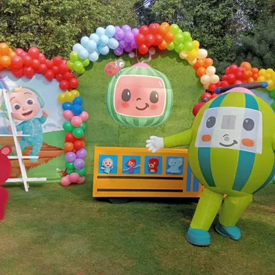 This Cocomelon setup is perfect for an outdoor garden party. It features a large backdrop with the show's characters, a balloon arch in rainbow colors, and even a mascot character for the kids to interact with.
