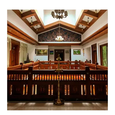The central courtyard, or 'muttam', is a key feature of this traditional Kerala style house. The intricately carved wooden railings and double-height space with a skylight create a bright and airy core for the home.