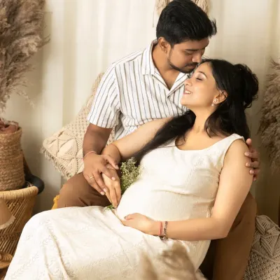 A tender moment from a boho maternity session, where a husband kisses his wife's forehead as they hold hands, both cherishing the anticipation of their new arrival.
