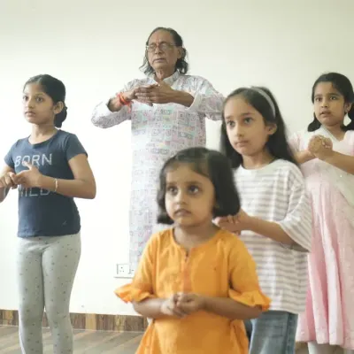 A beautiful moment capturing the Guru-Shishya parampara. An experienced guru patiently teaches the fundamentals of classical dance to a group of young, attentive students.