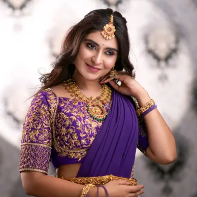A stunning close-up of our purple half-saree. The blouse features intricate gold embroidery, paired perfectly with traditional gold jewelry, also available for rent.