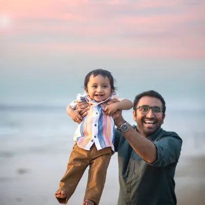 Flying high with dad! The beach at sunset provides the most beautiful canvas for joyful and energetic family moments like this one.