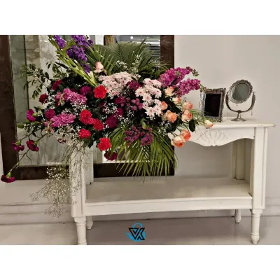A large, cascading floral arrangement on a console table. We use a mix of flowers and greenery to create arrangements that are full of texture, color, and life.