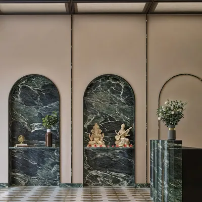 We believe in creating a sense of place, even in an office. This render shows how we integrated a mandir into the reception area using arched niches of green marble, creating a serene corner that feels both spiritual and seamlessly part of the overall design.