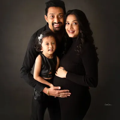 A beautiful family portrait in coordinated black outfits. Big sister is looking so proud and excited to welcome her new sibling.