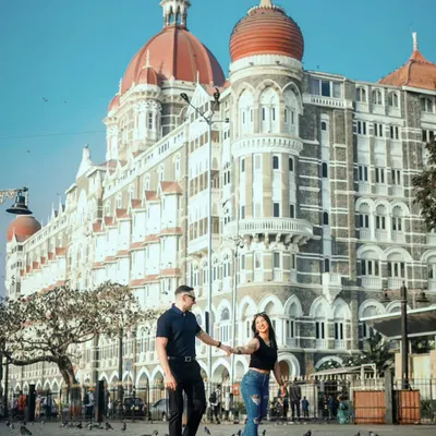 A classic Mumbai pre-wedding shot. The couple walks hand-in-hand in front of the magnificent Taj Mahal Palace Hotel, creating an iconic and timeless memory.