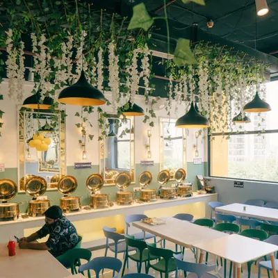 A wide view of my restaurant's interior. I love the hanging greenery and modern light fixtures that create a warm and inviting ambiance for my guests.