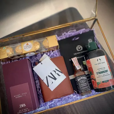 A luxury gift hamper for that special someone. This glass box includes a Zara perfume and wallet, Body Shop shower gel, Ferrero Rocher, a Jack Daniel's miniature, and a Man Company sheet mask.