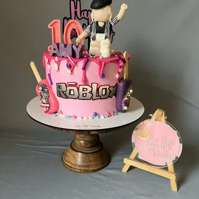 Perfect for a gamer's 10th birthday, this Roblox-themed cake features a pink drip design and is topped with a custom fondant character. The details include the Roblox logo and other game-inspired accents.