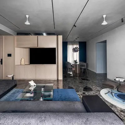 The full L-shaped living room, showing the formal and informal seating areas unified by Ceppo De Gre marble flooring and a large blue area rug.