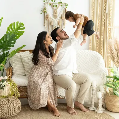 A playful and heartwarming family photo. The father lifting his baby high in the air captures a moment of pure, unfiltered happiness that makes for a wonderful memory.