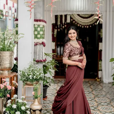 A modern reception look featuring a custom-made fish-cut skirt in a deep maroon. The skirt is paired with an embroidered blouse and a draped dupatta, elegantly cinched at the waist with a belt to create a sophisticated and contemporary silhouette.