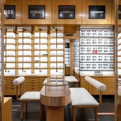 A view of the EYE 2 EYE LUXE eyewear store, where I designed custom furniture and display units. The space uses mirrors to create an illusion of depth, reflecting the warm wood and elegant seating.