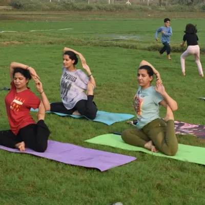 A group of students practicing Mermaid pose in the park. Doing yoga outdoors helps us connect with nature and feel more grounded.